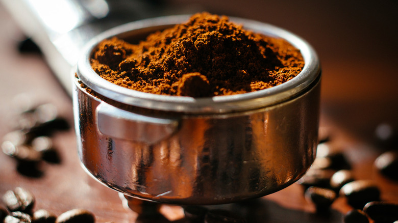 An espresso machine filter holds freshly ground coffee.