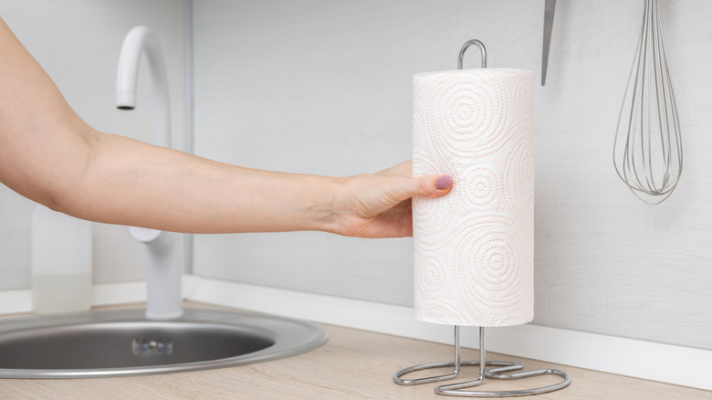 Person putting paper towel on metal holder