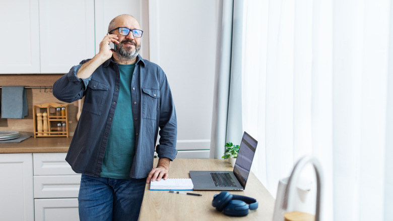 Man talking on the phone in an all-white kitchen