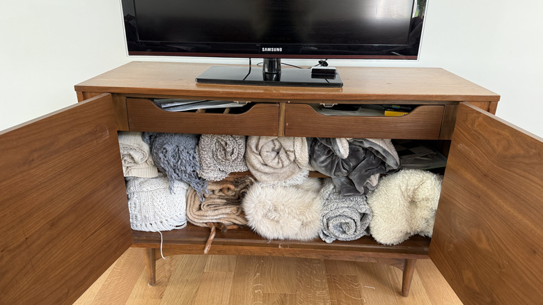 Blankets rolled up in TV stand