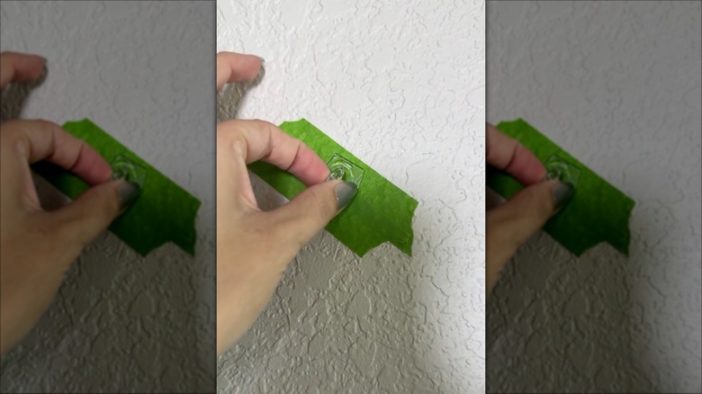 Command hook hot glued to green tape on the wall for temporarily hanging decor