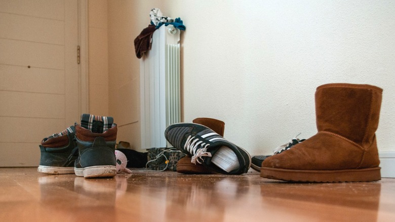 Cluttered shoes lying on hardwood floor in entryway