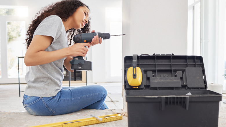 Woman drilling a hole at the top of stairs