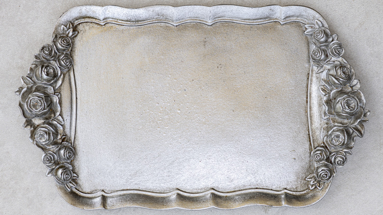 Steel tray with floral designs on either side of it.