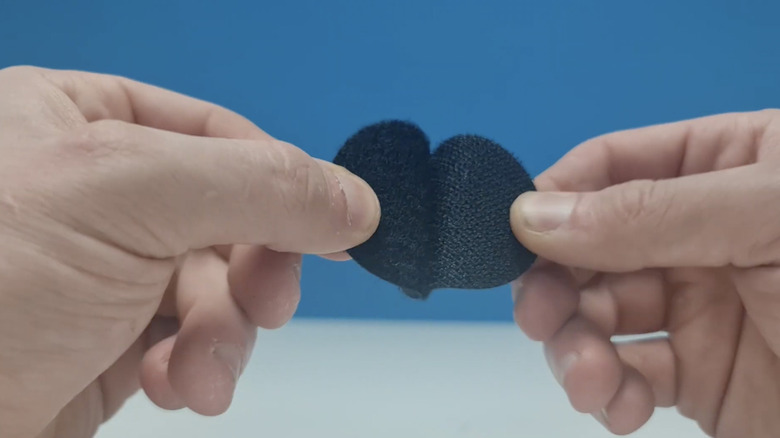 Screenshot of a person pulling two velcro dots apart with hands