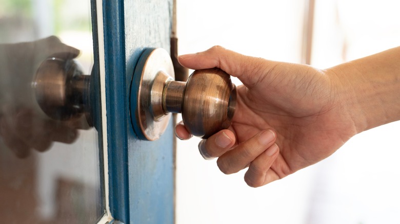 Hand touching bronze doorknob