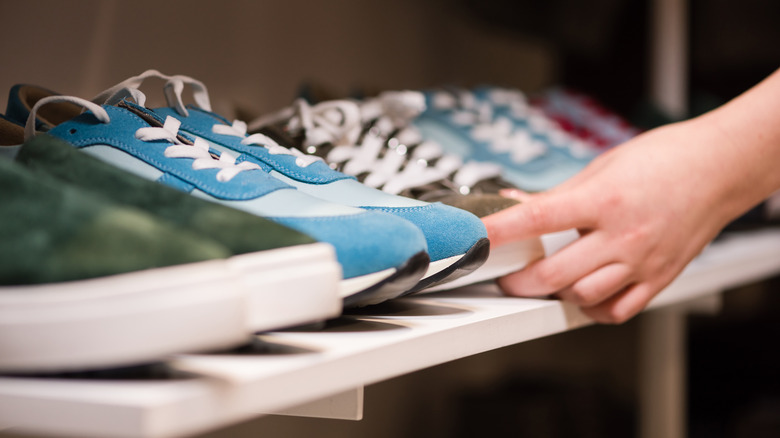 A person putting away shoes on a shelving unit