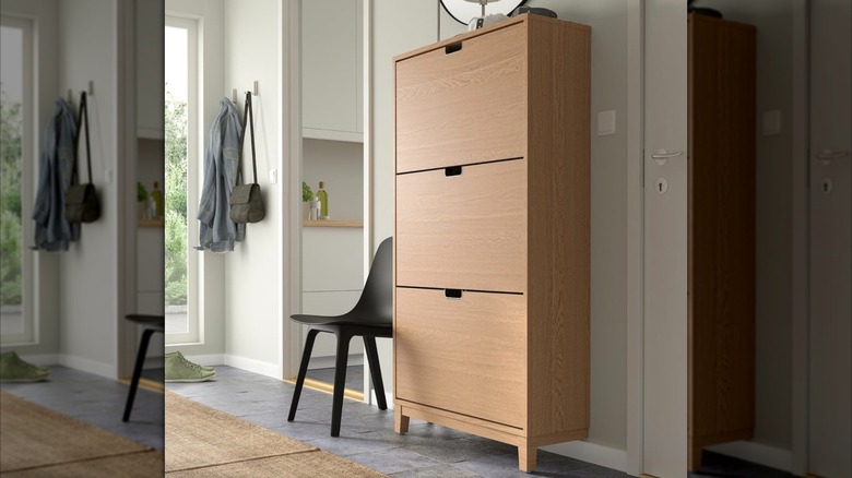 STÄLL Shoe cabinet in an entryway with a black chair next to it
