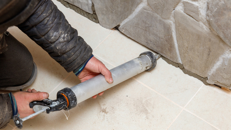 Close up of person filling in crack with caulk