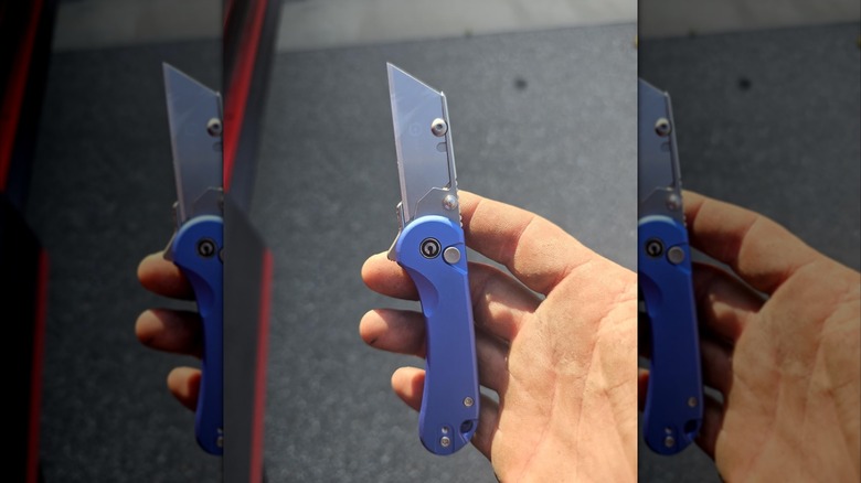 Hand holding box cutter with blue handle