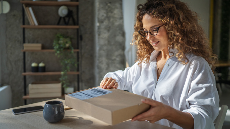 Woman sitting at a desk, opening a package