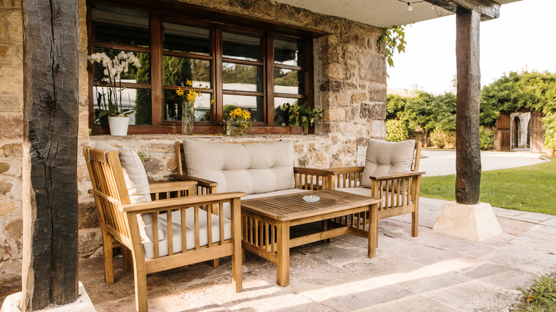 A rustic patio set up with chairs, a couch, and a coffee table