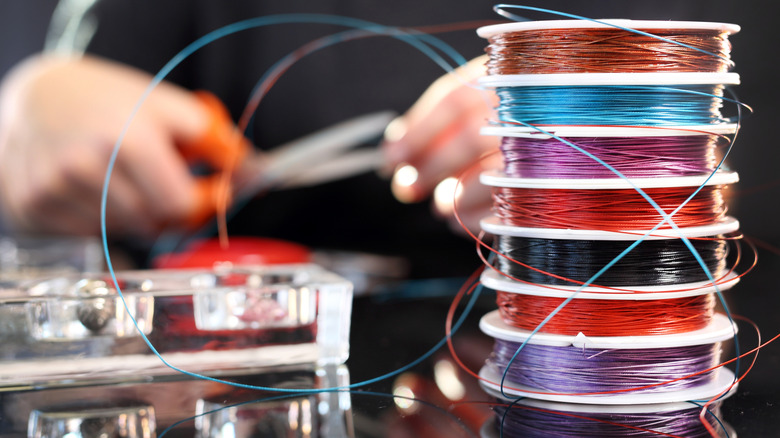 A person cuts colorful craft wire with a pair of scissors.
