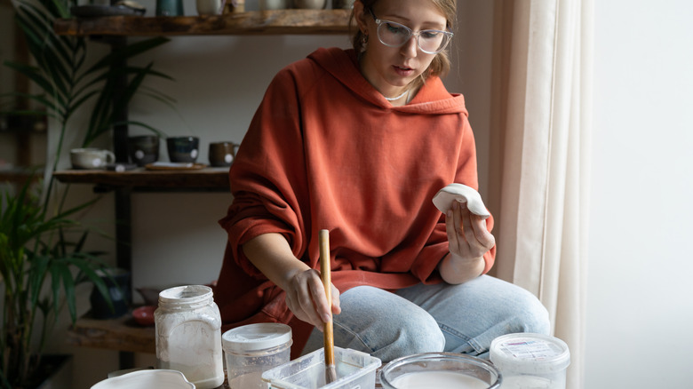 A ceramic maker applies a sealant to her clay art piece.