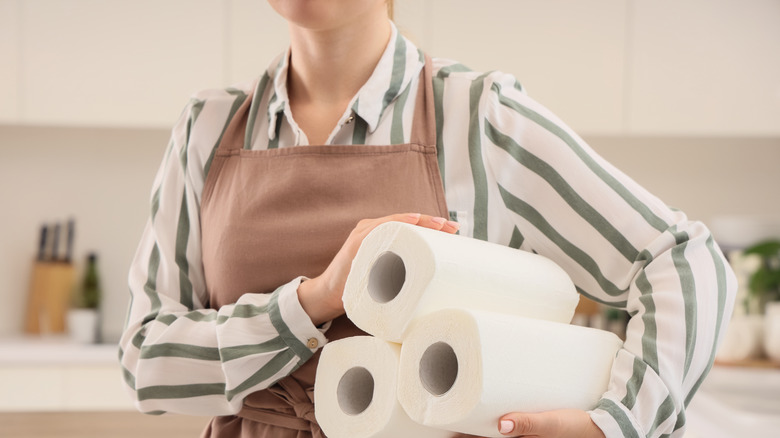 Woman holding 3 paper towel rolls under her arm