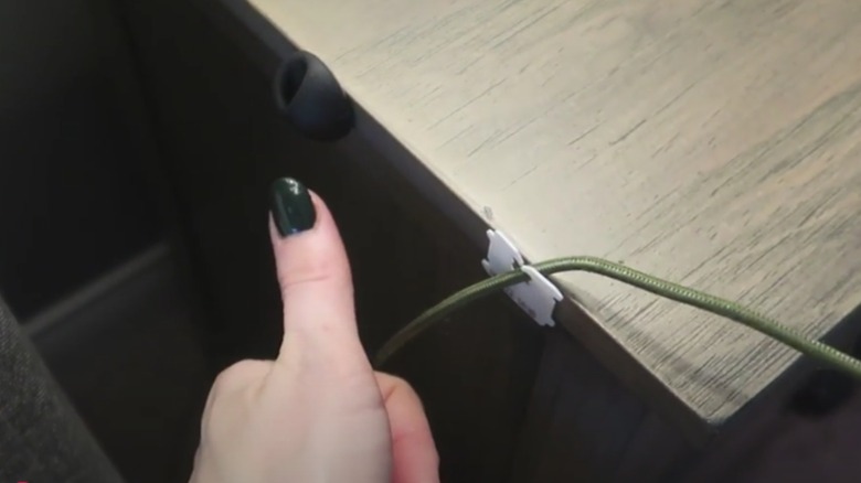 Bread tag taped to a nightstand propping up a phone charging cable