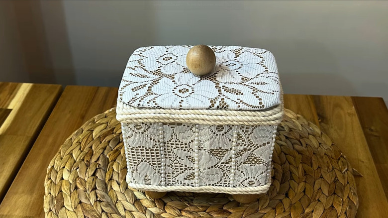 A DIY storage box made from cardboard, toilet paper tubes, and old lace
