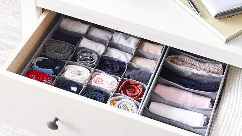 Drawer with organizer sets holding clothing items.