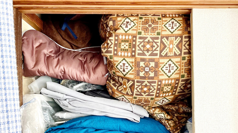 Blankets stuffed into the top of a closet.