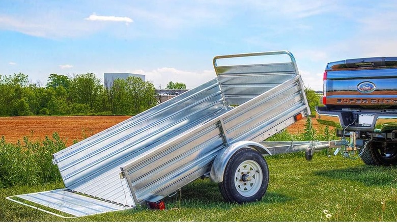 Alloy steel utility trailer hitched to back of pickup truck in field