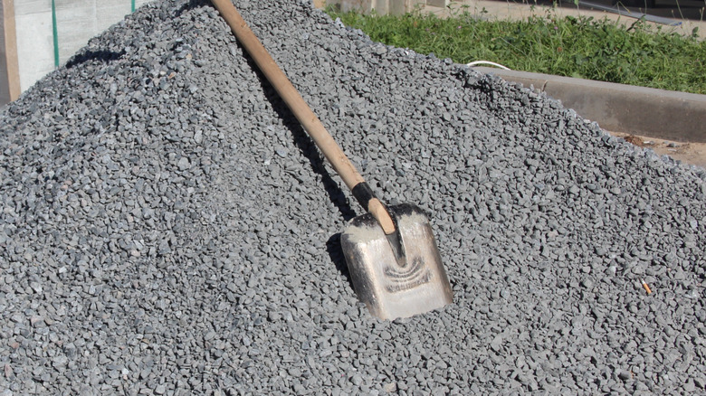 Pile of gravel with shovel in a backyard.