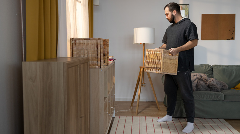 A man holds a square wicker wood basket