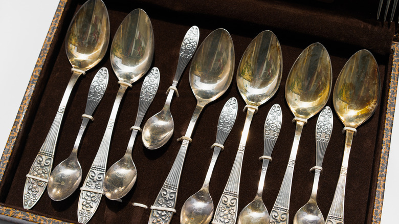 A box of vintage silver spoons held in place with ties