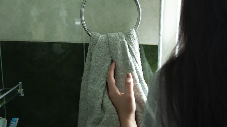 A person wiping their hands on a towel stored on a metal towel ring