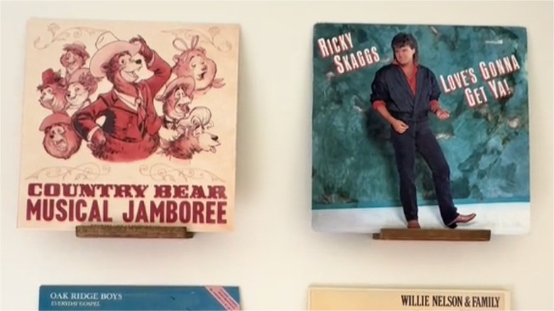 Records displayed on wall with wood shelf