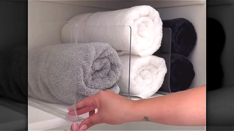 Rolled towels on a shelf with clear acrylic dividers in between