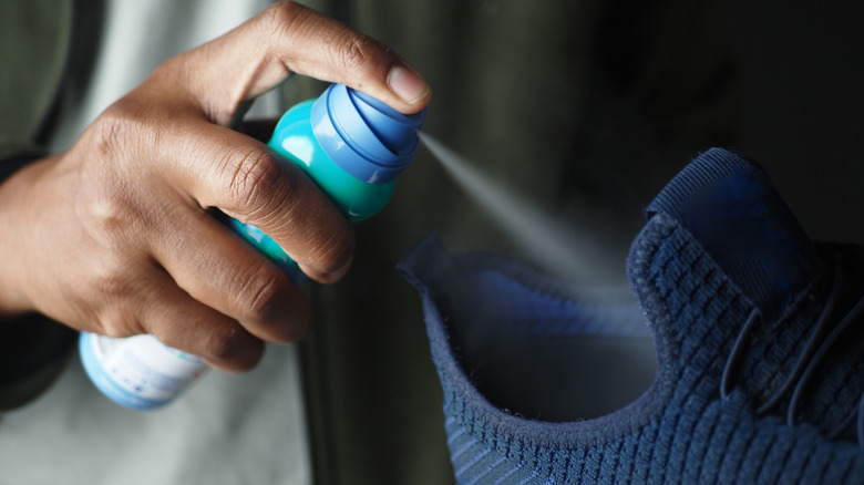 Person spraying cleaner inside a blue shoe