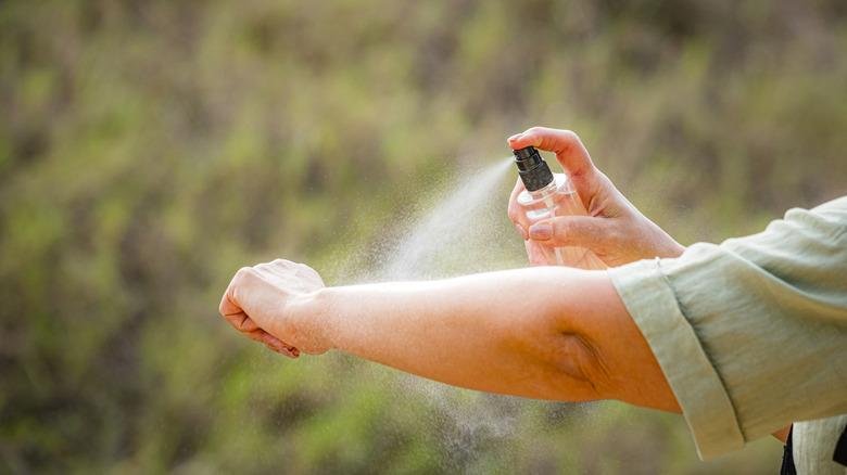Person spraying insect repellent on arm