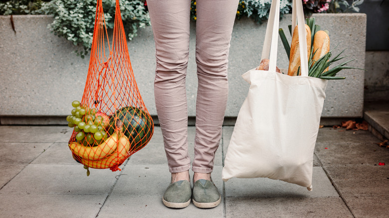 A person carrying two reusable shopping bags
