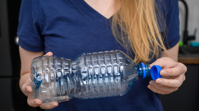 woman holding empty plastic bottle