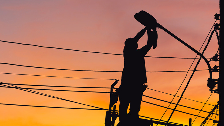 Utility worker changing streetlight bulb
