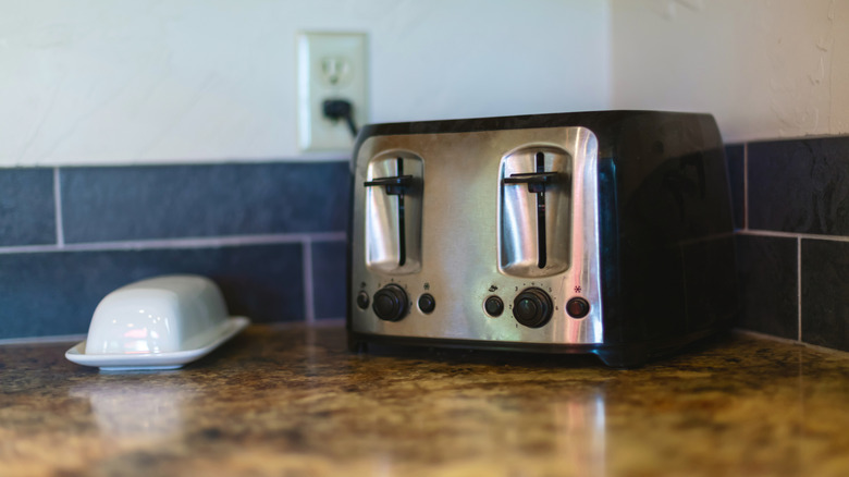 A toaster sitting on a countertop next to a butter dish