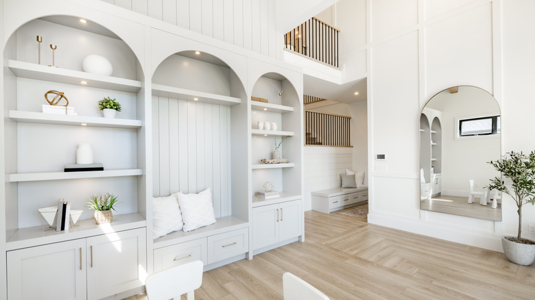 Living room interior with white decor arched mirror and built in shelving