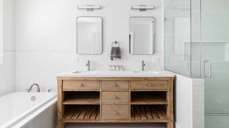 A bathroom with a natural wood cabinet with a white marble counterto