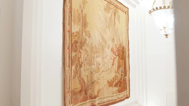 Antique tapestry hangs on the wall of a stairway.