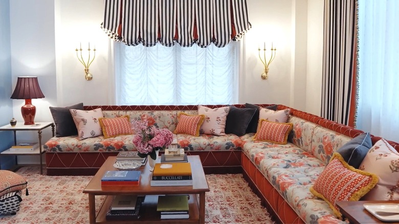 Luxurious living room with large sofa in a floral print, striped curtains, and large area rug.