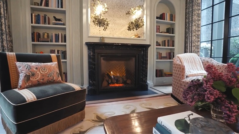 Living room with two armchairs and a black marble fireplace.