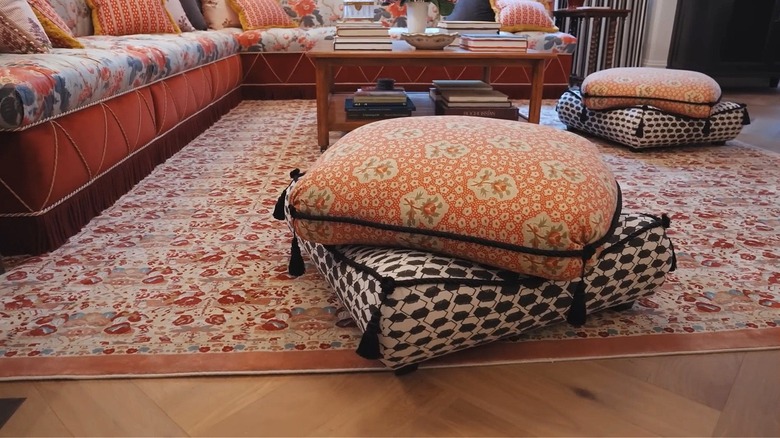 Poufs in different patterns stacked on top of each other over a printed rug.