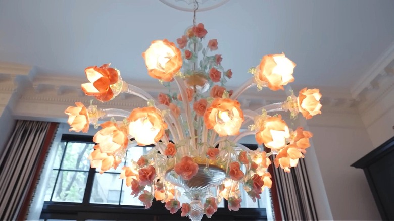Large glass chandelier decorated with pink flower details hangs from the ceiling.