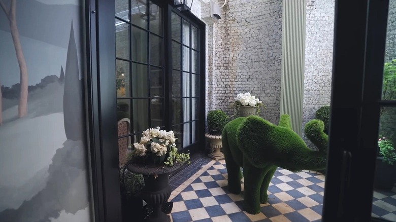 A topiary elephant in a terrace with checkerboard stone floors.