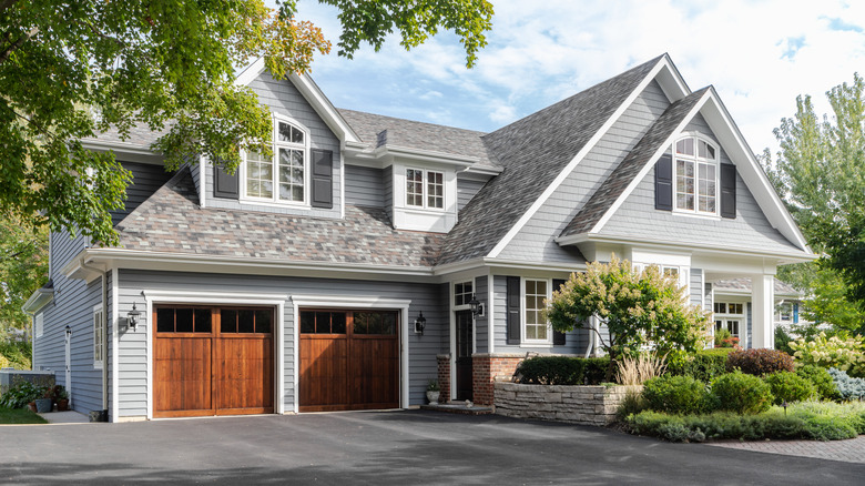 The exterior of a light gray house with a brown wooden two-car garage