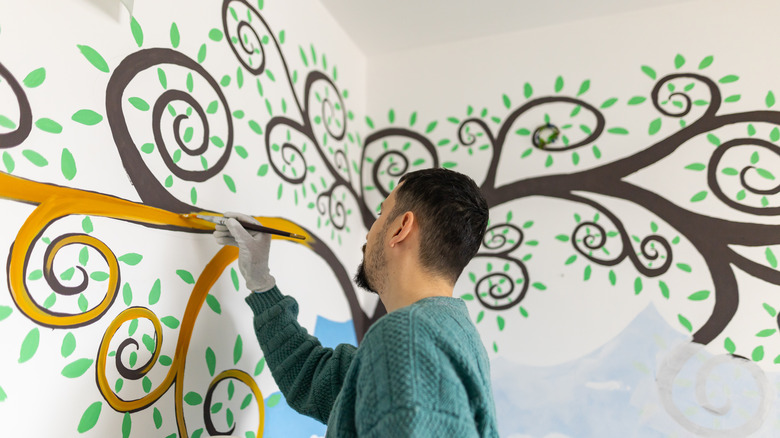 man painting mural on wall
