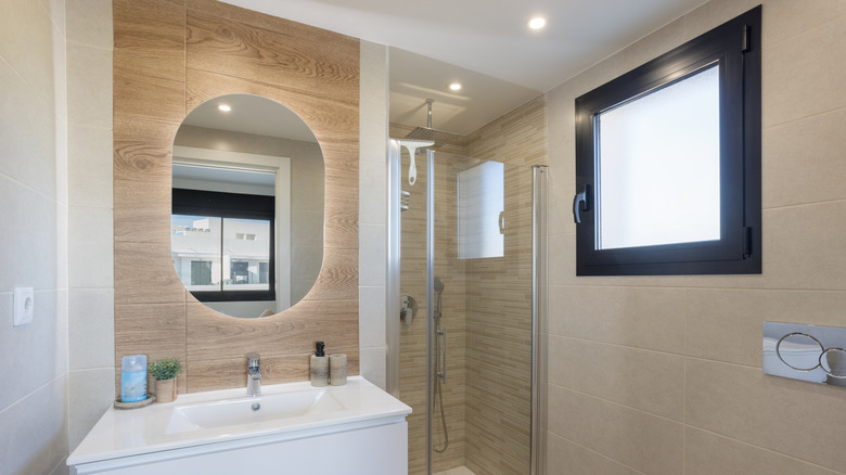 Wood panels act as a subtle accent wall behind the bathroom mirror and sink