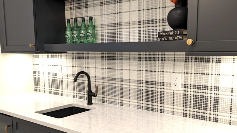 A kitchen backsplash with a plaid design created out of mosaic tiles
