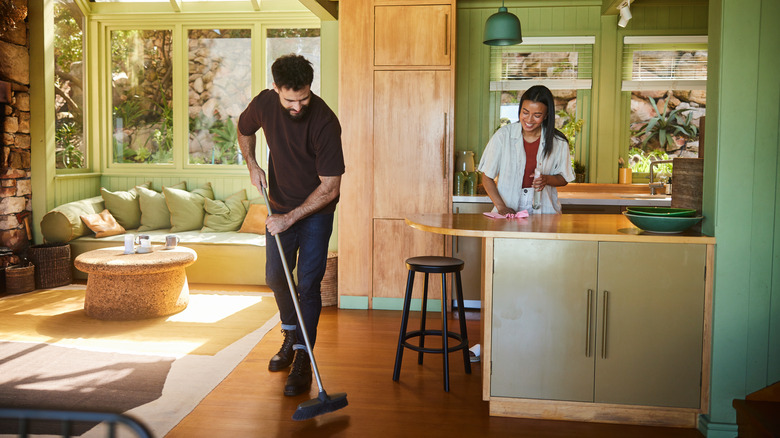 A smiling couple cleaning their floor and countertop