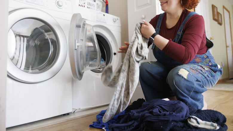 Woman loading dirty clothes into the washing machine
